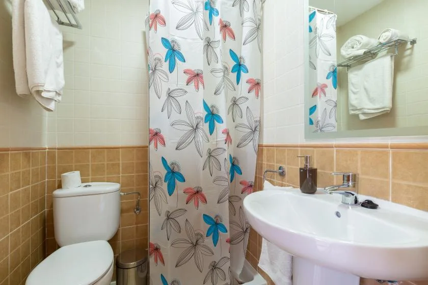 A bathroom with a floral shower curtain, toilet, and sink.