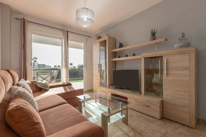 A living room with seating, a glass coffee table, and a television.