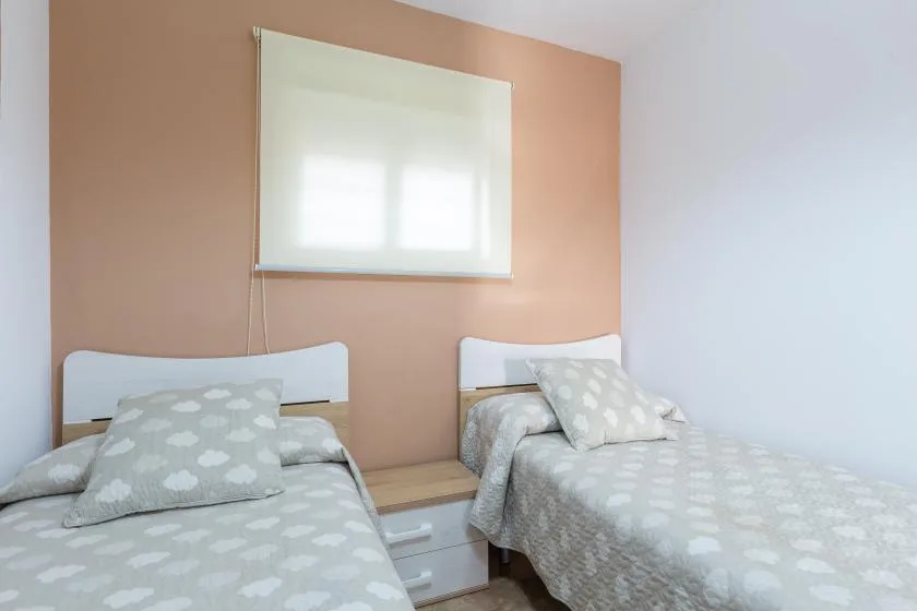 A twin bedroom with two beds dressed in pale patterned bedding.