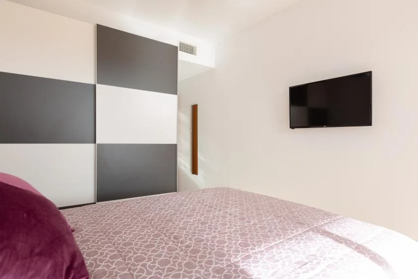 A bedroom with patterned bedding and a wall-mounted television.