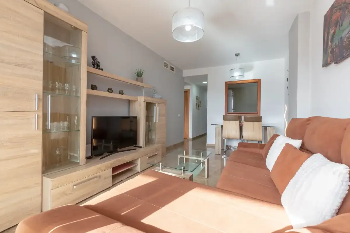 A living room with seating, a television, and a glass coffee table.