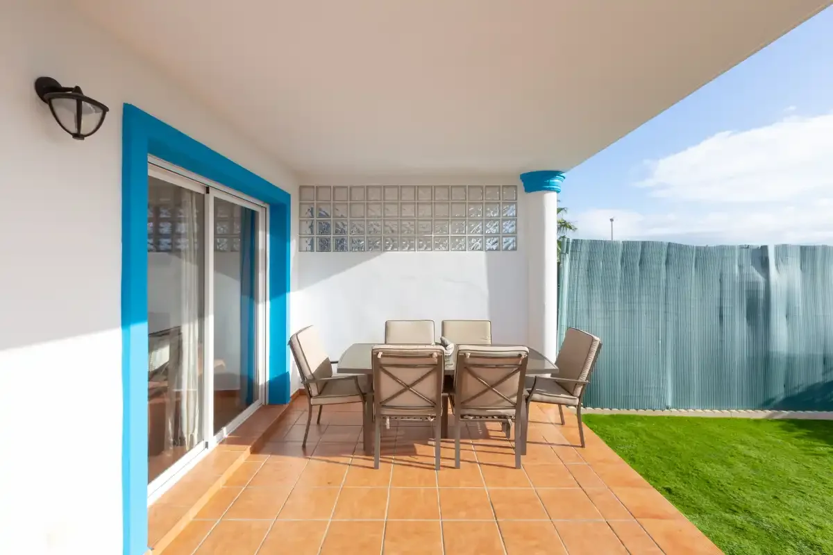Covered patio with a dining table and chairs beside sliding glass doors.
