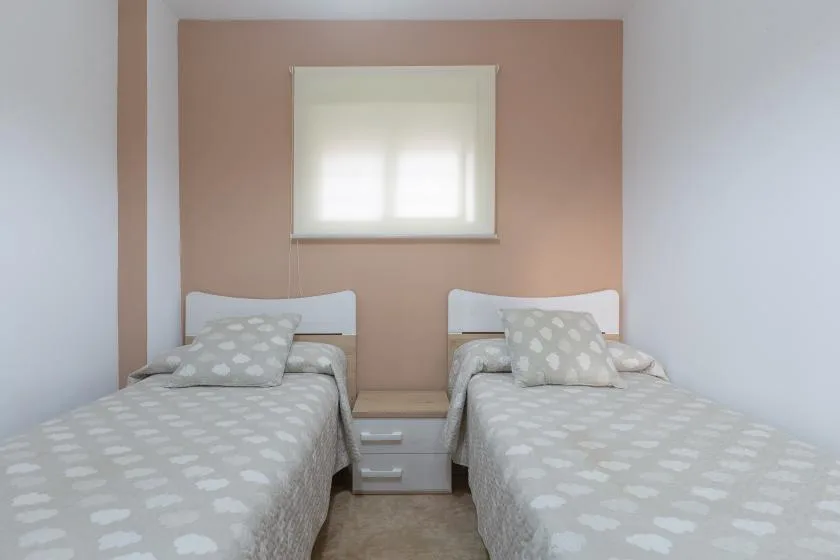 A bedroom with two single beds beneath a window.