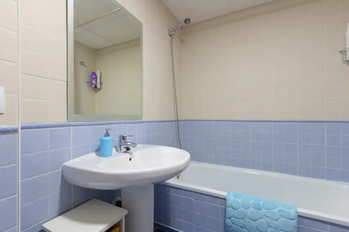 A bathroom with a sink, mirror, and bathtub.