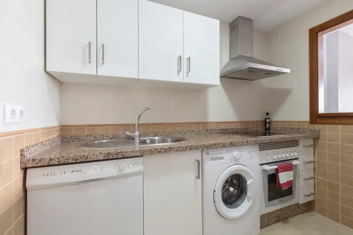 A compact kitchen with white cabinets, a sink, and built-in appliances.