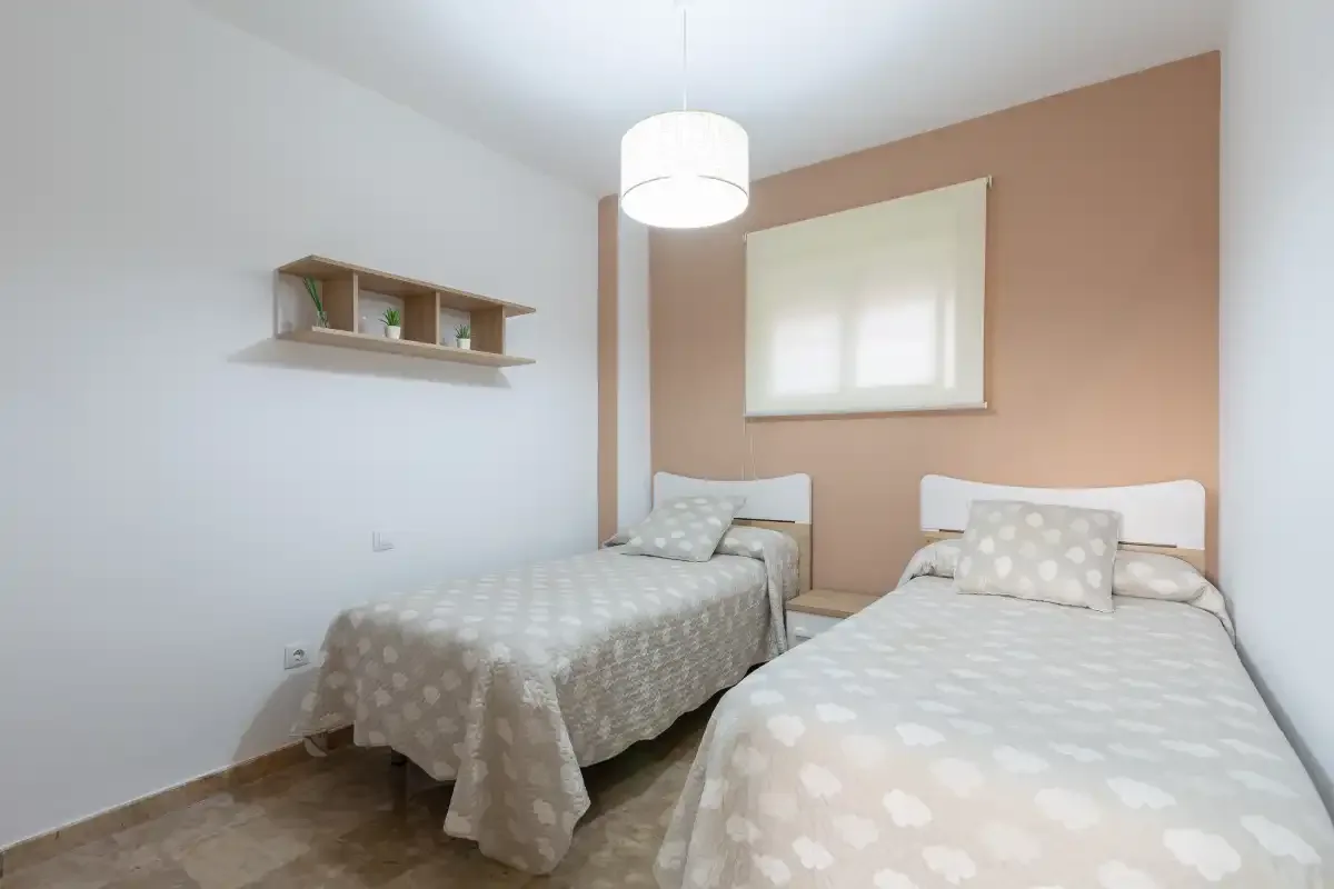 A bedroom with two beds and a window on the back wall.