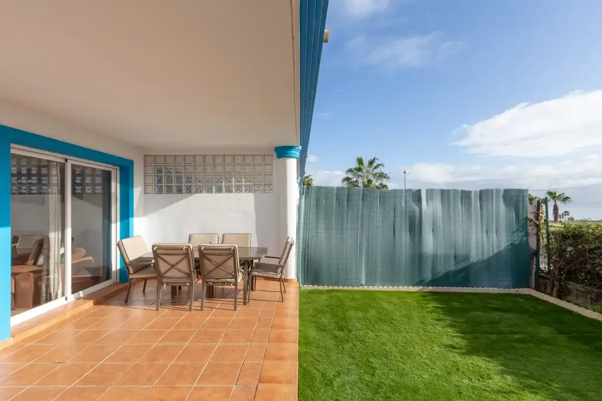 A patio with outdoor seating opens onto a small lawn.