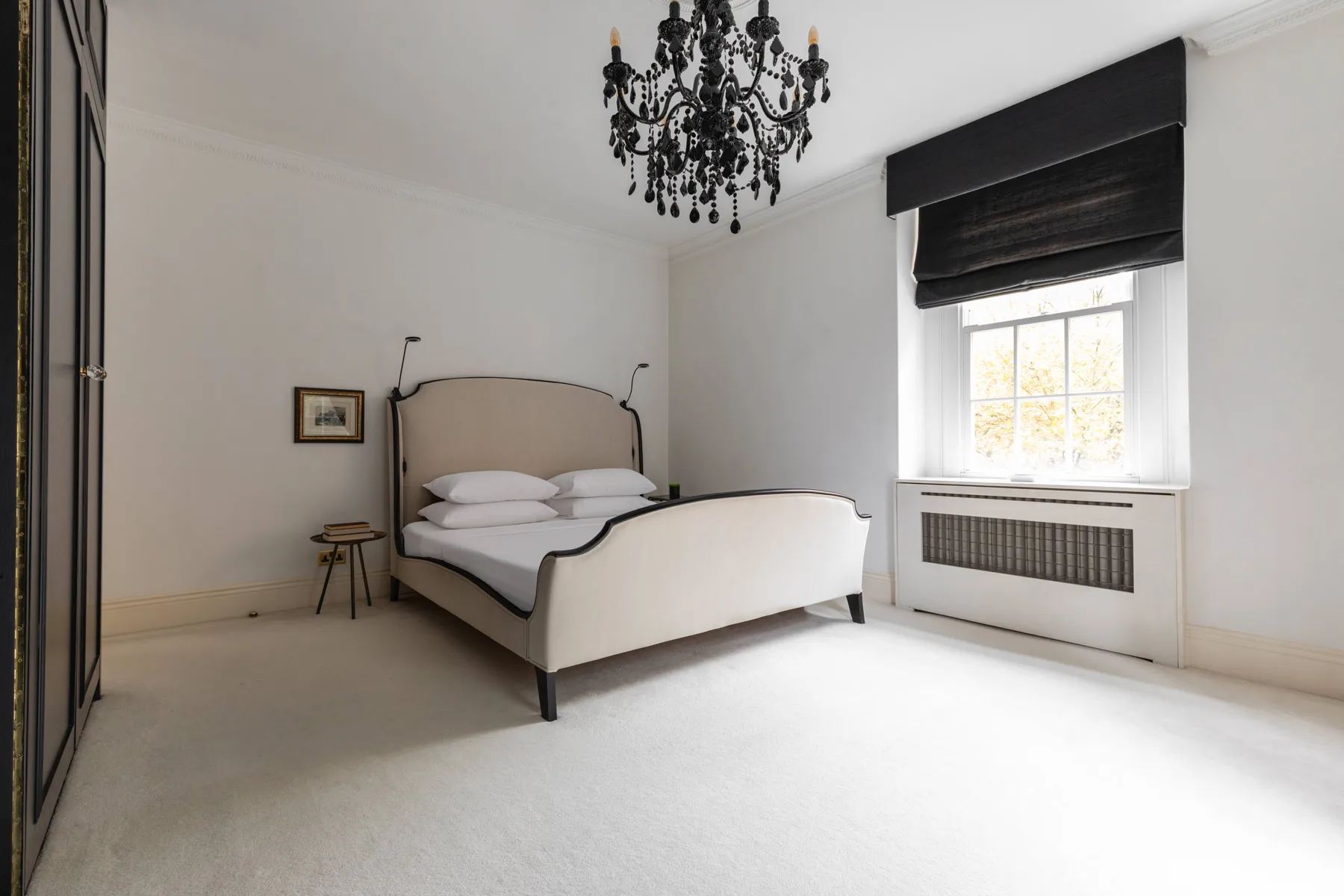 A bright bedroom with a bed beside a sunlit window.