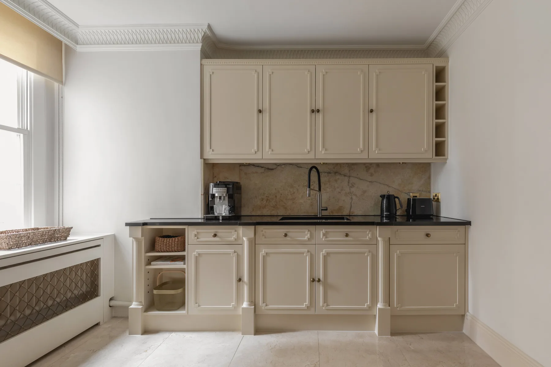 A bright kitchen with cream cabinets, a countertop, and a sink.