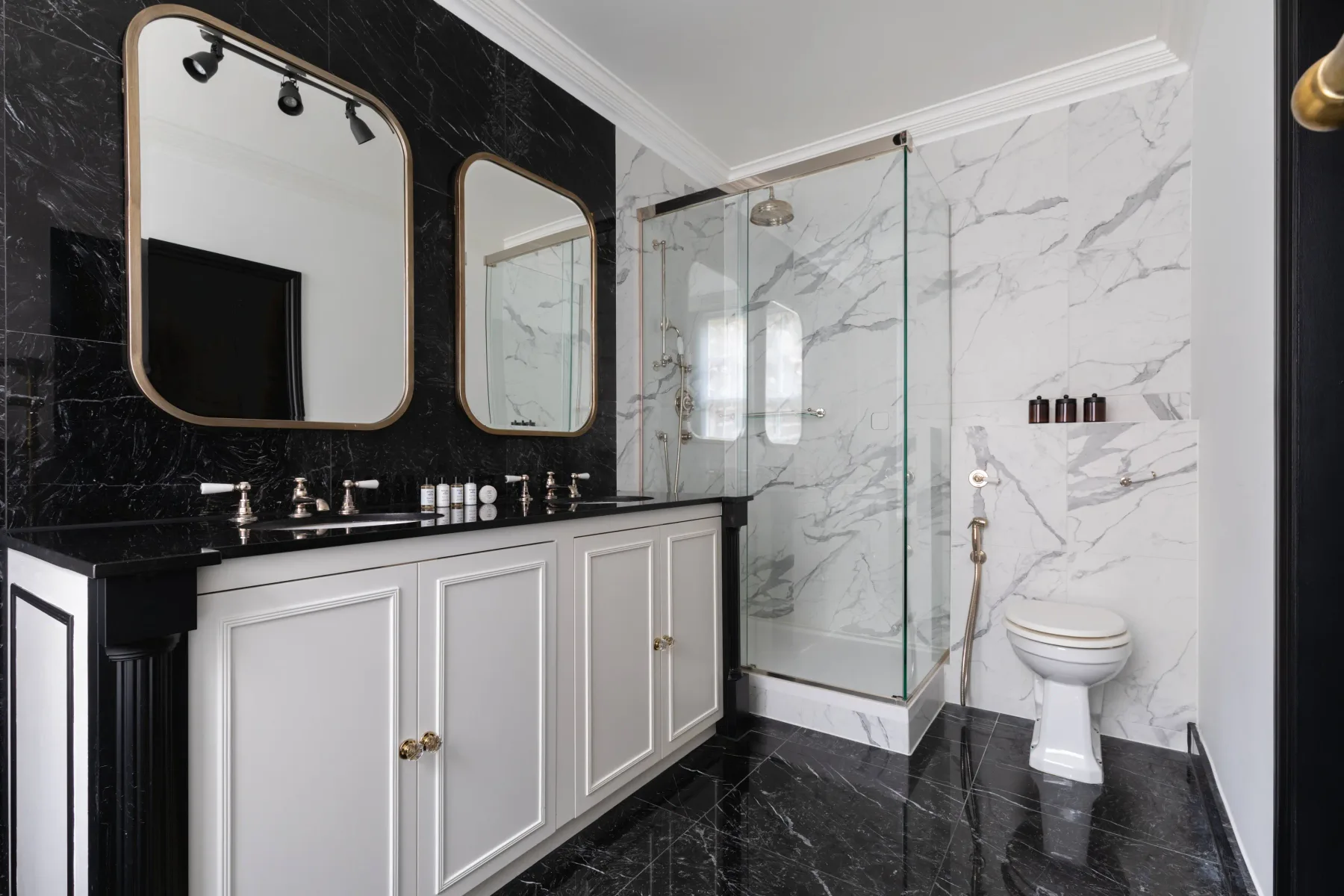 A bathroom with a long vanity, mirrors, and a glass shower.