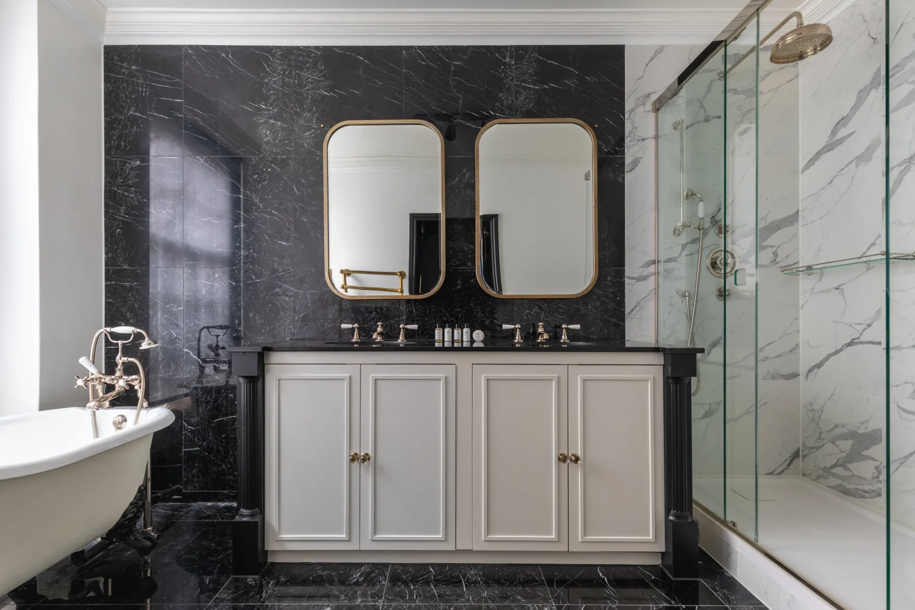A bathroom with a double vanity, two mirrors, and a glass shower.
