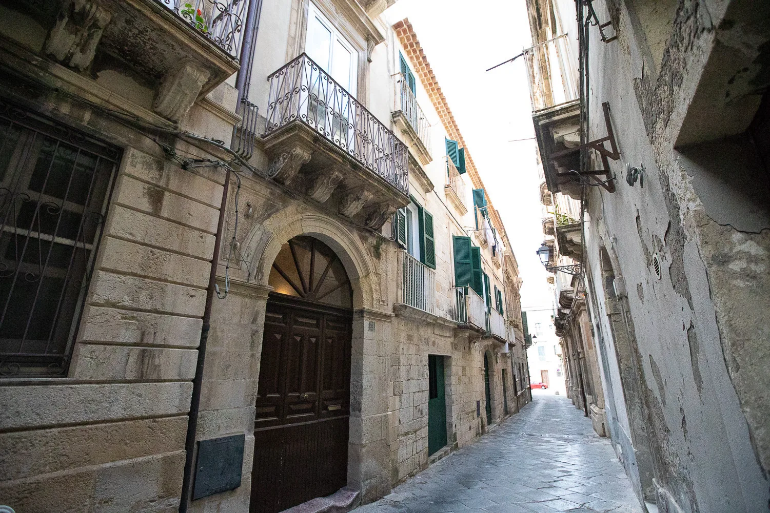 Una calle estrecha pavimentada con piedra pasa entre edificios muy próximos.