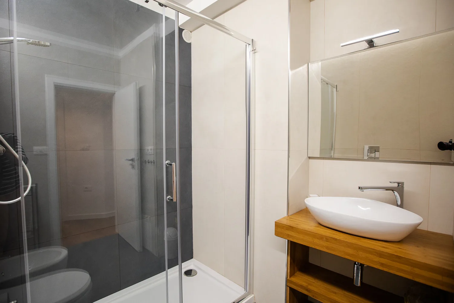 Un baño con una ducha de vidrio y un lavabo sobre un mueble de madera.