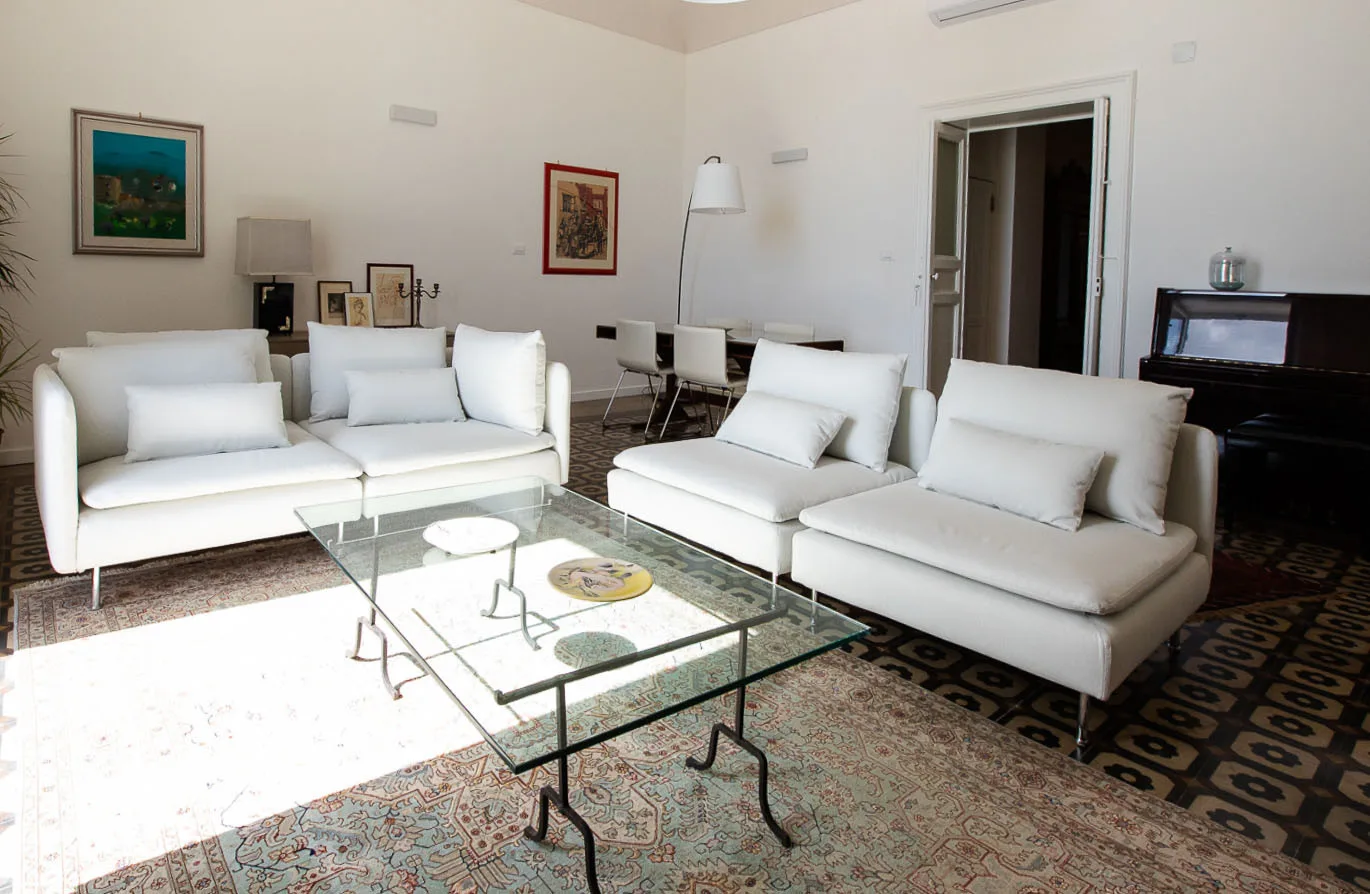 Una sala luminosa con asientos blancos dispuestos alrededor de una mesa de centro de vidrio.