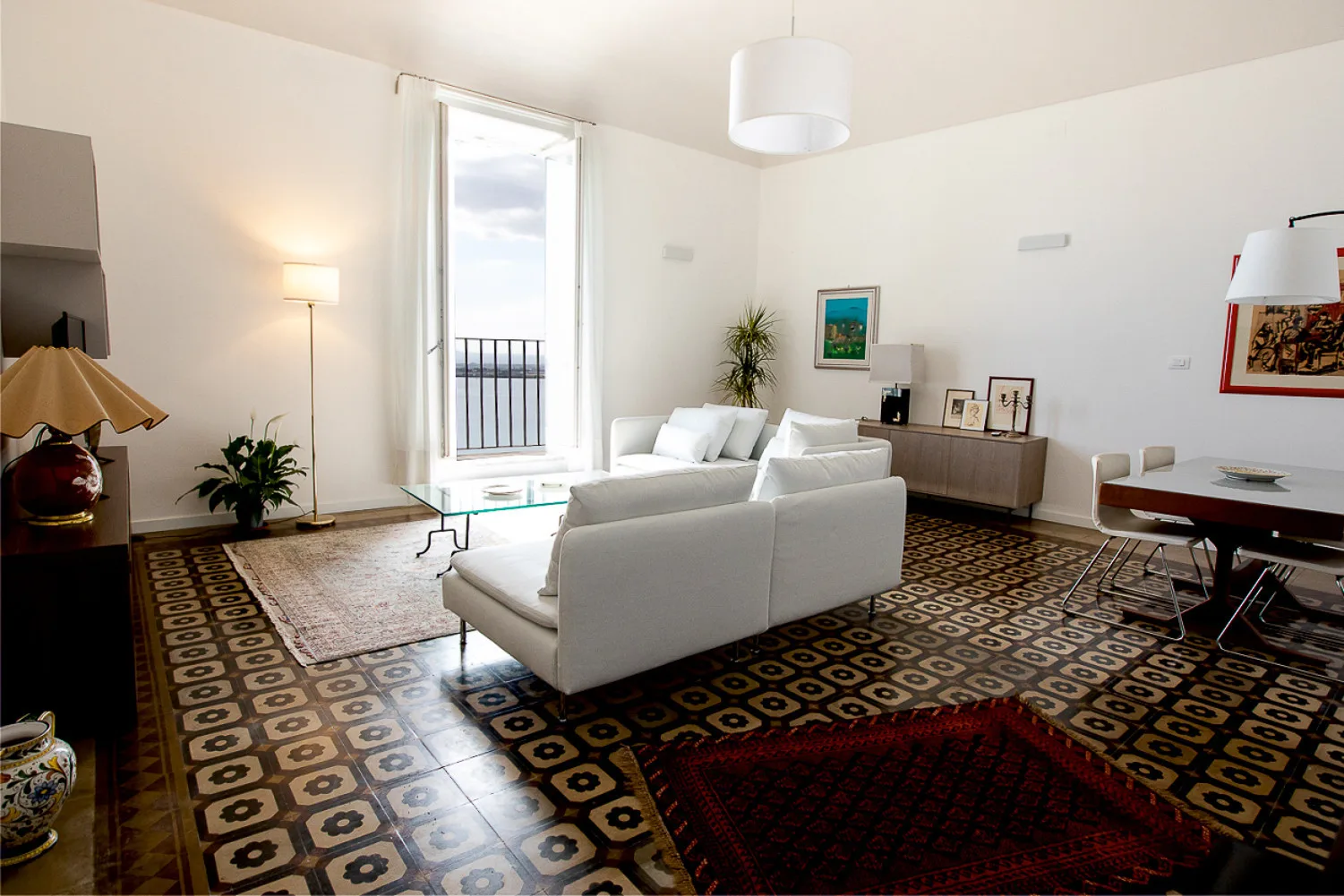 Una sala luminosa con asientos, alfombras estampadas y una ventana alta.