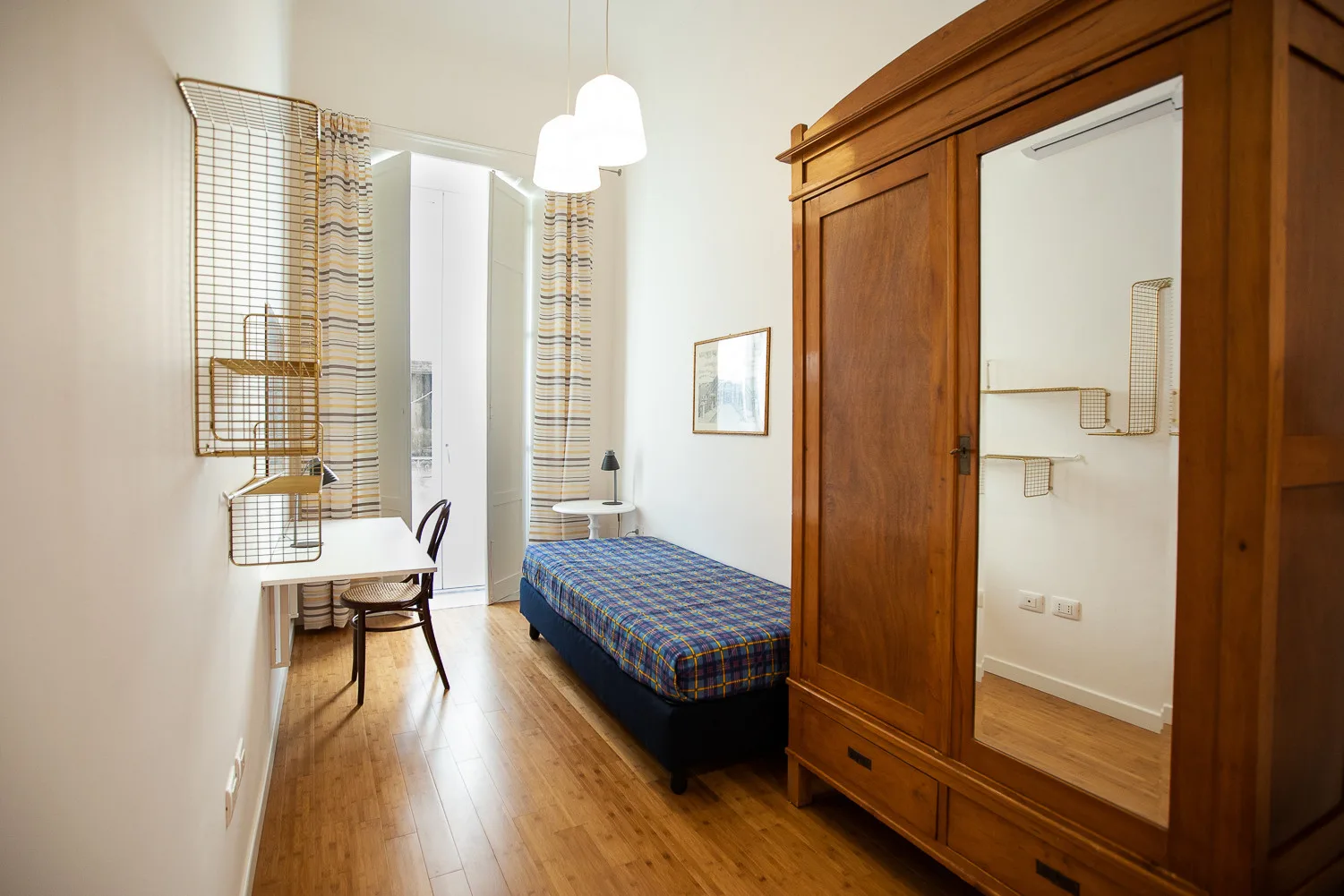 Un dormitorio con una cama individual, un armario de madera y un escritorio.