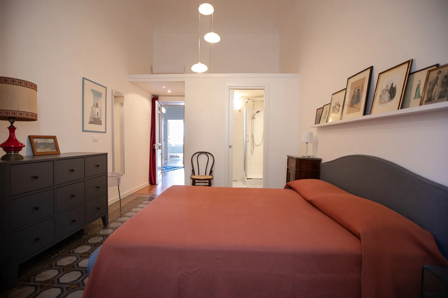 Dormitorio con una cama grande, una cómoda oscura y cuadros enmarcados en la pared.