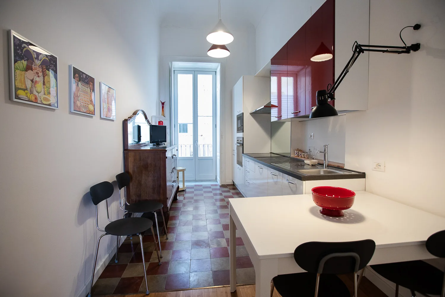 Una cocina luminosa con una encimera larga y una mesa blanca.