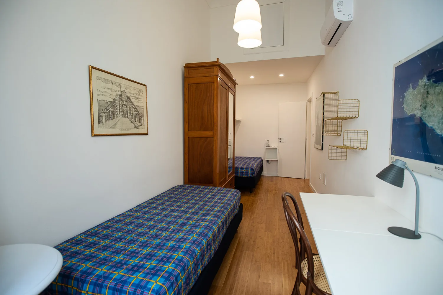 Un dormitorio compacto con dos camas, un armario de madera y un escritorio.