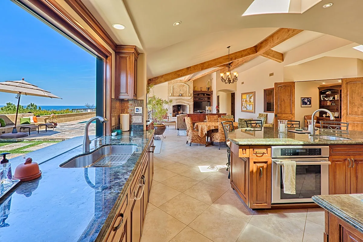 An open kitchen and dining area with a large window overlooking an outdoor patio.