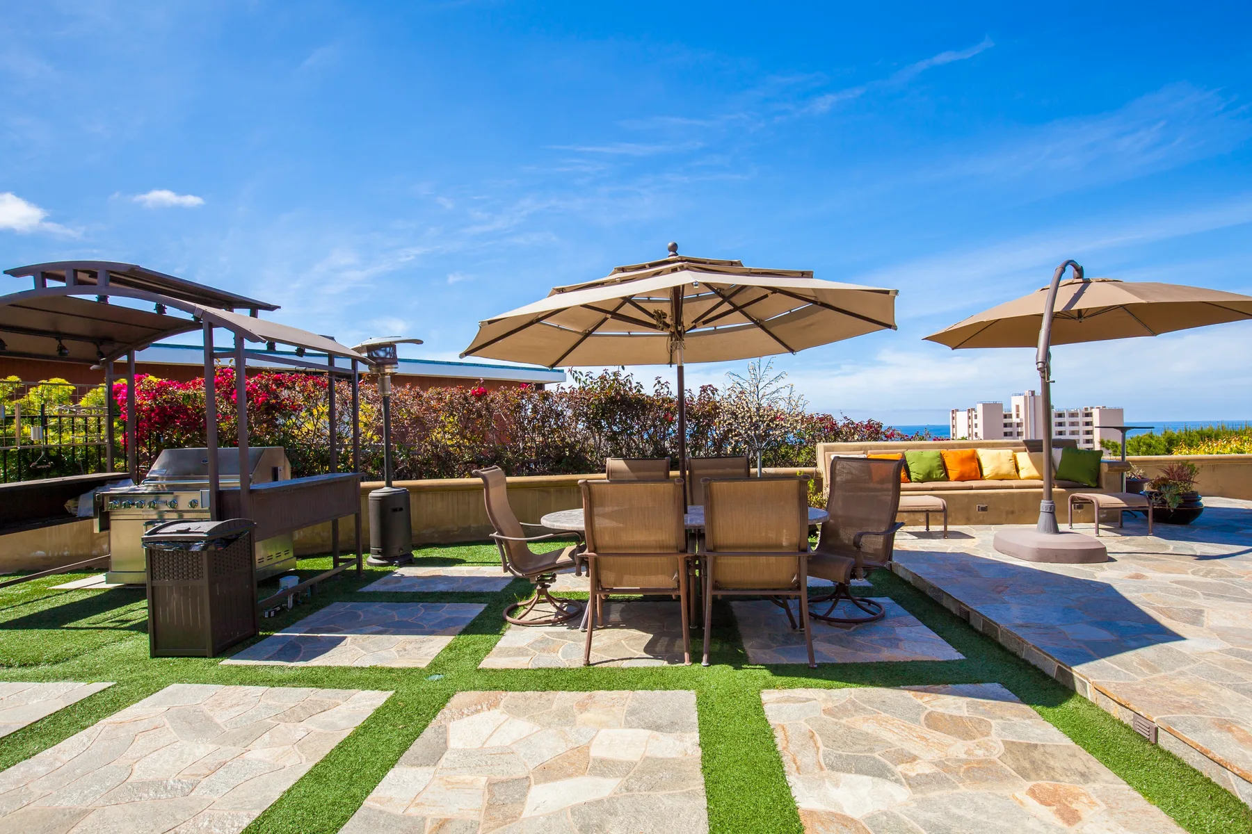 An outdoor patio with a dining table, seating, and large umbrellas.