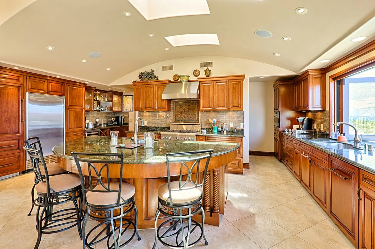 A spacious kitchen with wooden cabinetry, a central island, and a dining area.