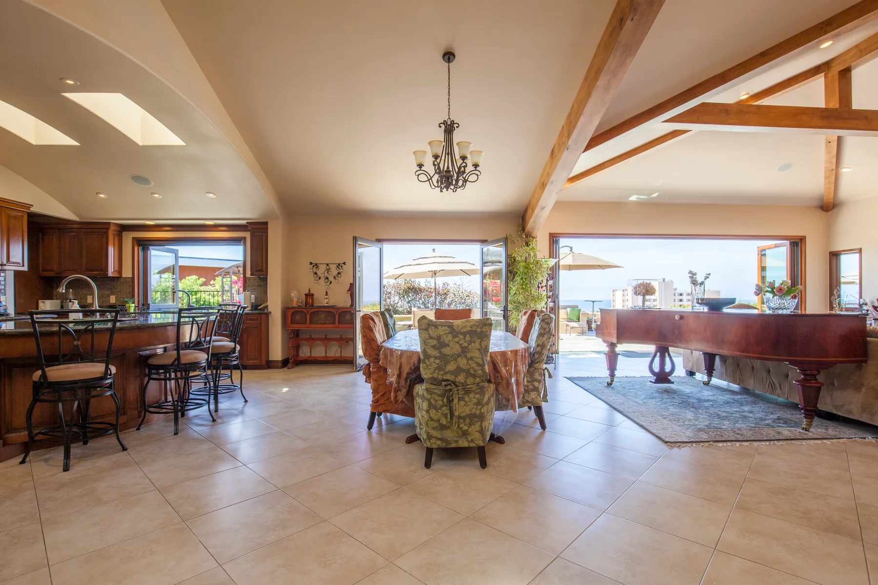 An open-plan dining and living area with a table, seating, and a grand piano.
