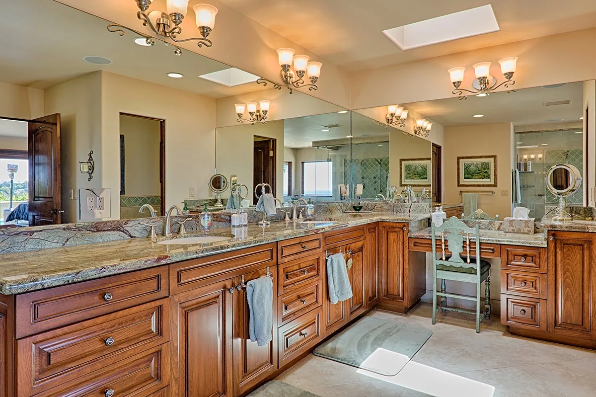 A spacious bathroom features long wooden vanities, wide mirrors, and a double sink.
