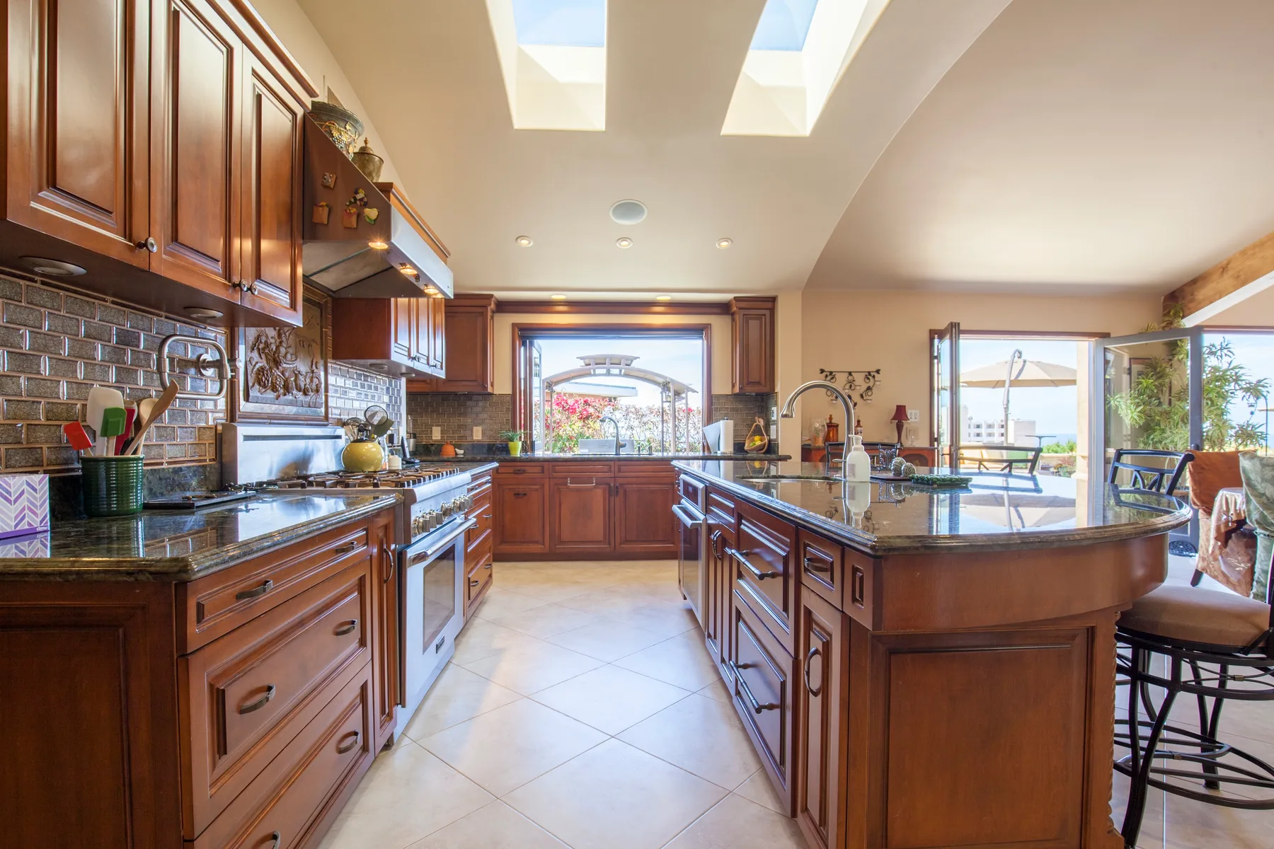 A spacious kitchen with wooden cabinets, a central island, and skylights.