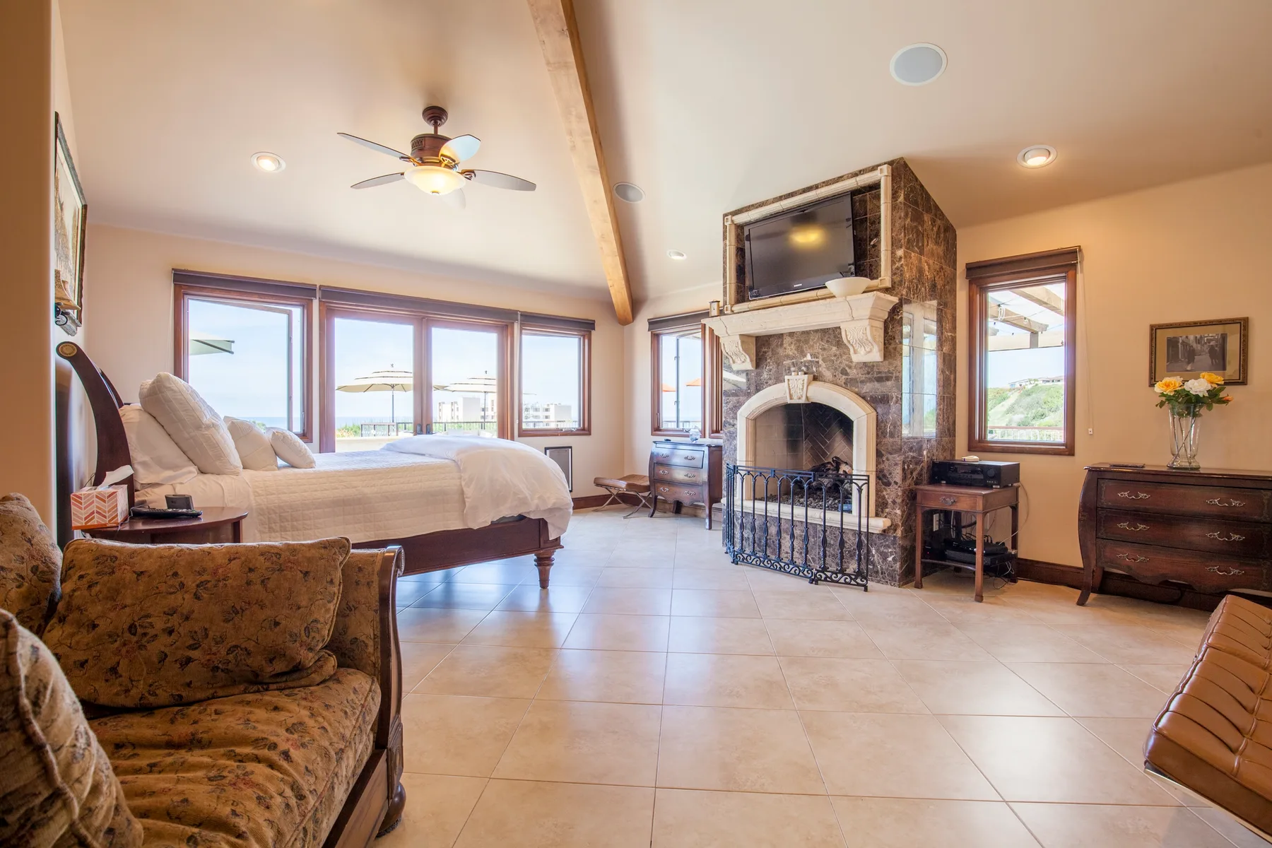 A bedroom and sitting area share a bright open room with a fireplace.