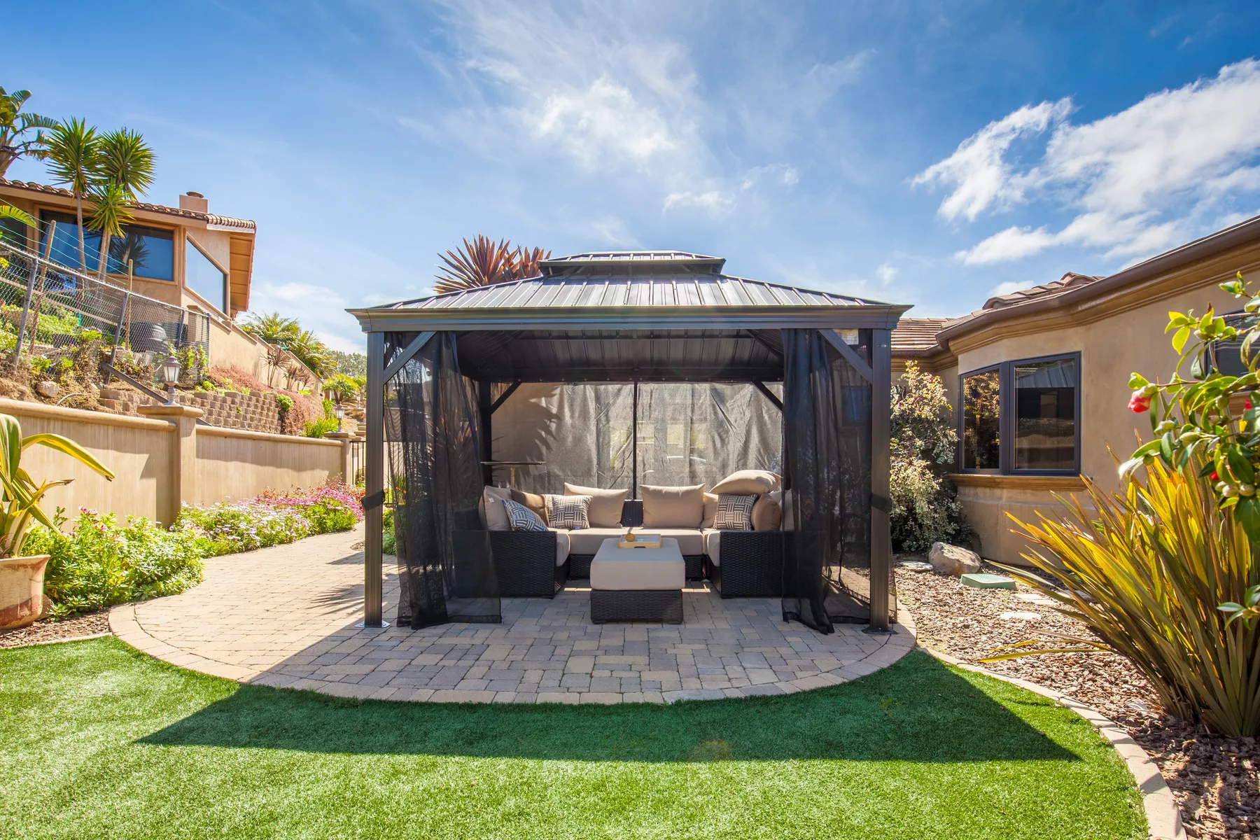 A covered outdoor seating area opens onto a garden lawn.