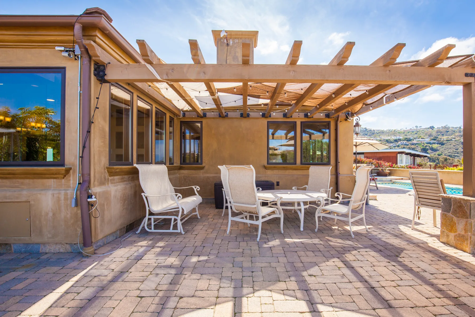 A shaded patio with outdoor seating beneath a wooden pergola.