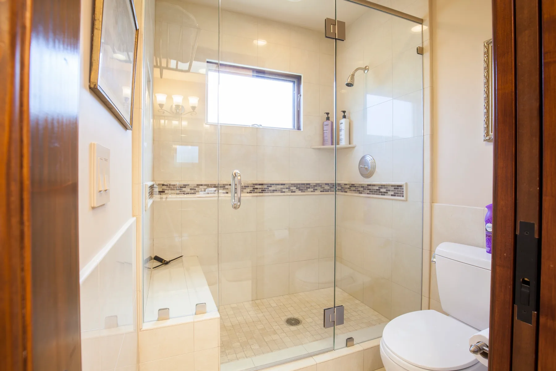 A tiled bathroom with a glass shower and a toilet.