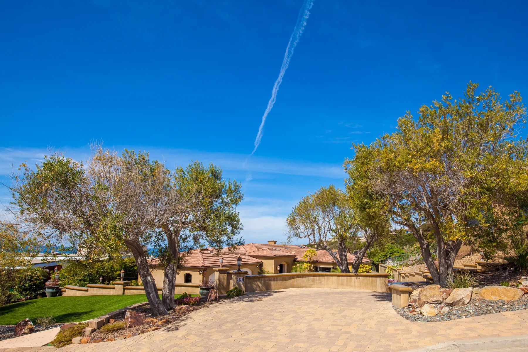 A paved courtyard bordered by mature trees and landscaped greenery.