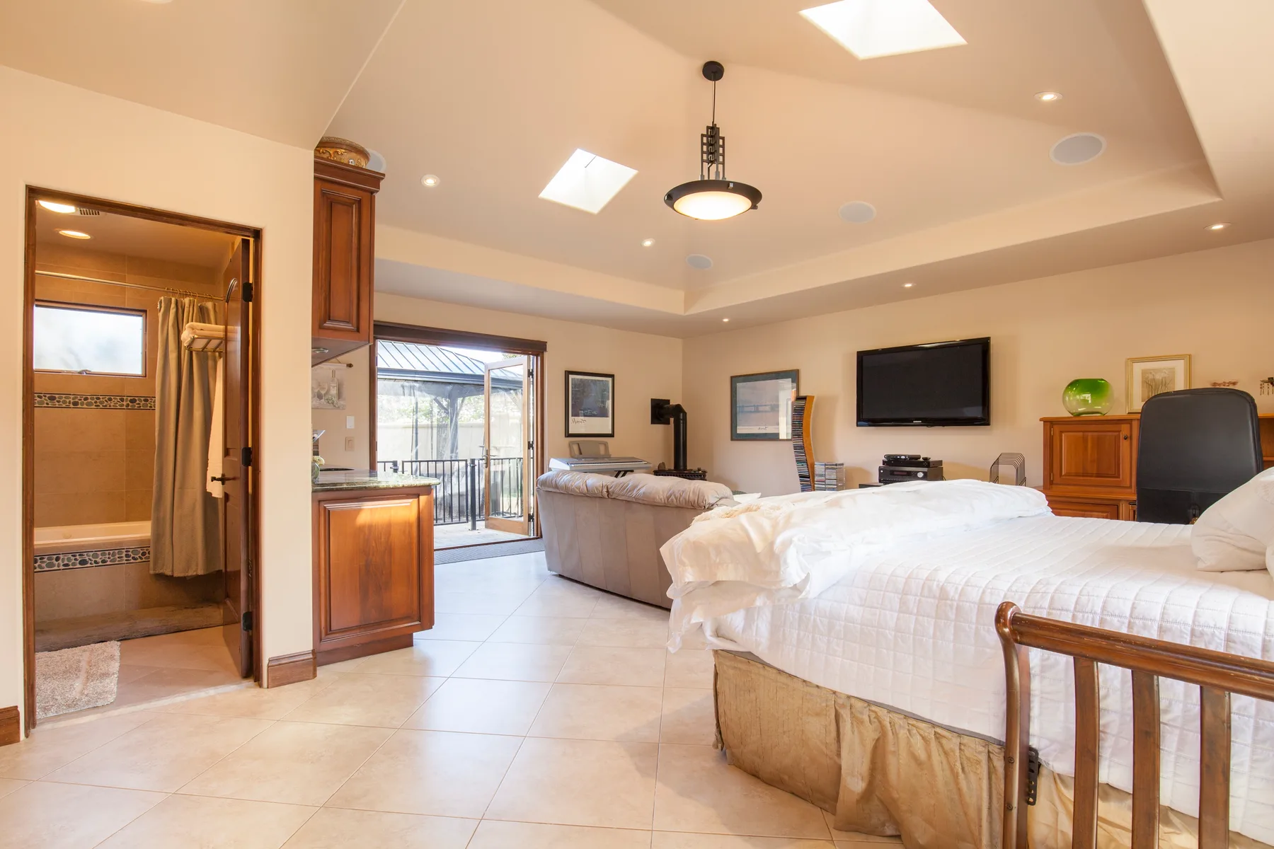 A bedroom and sitting area with a bed, sofa, and sliding glass doors.