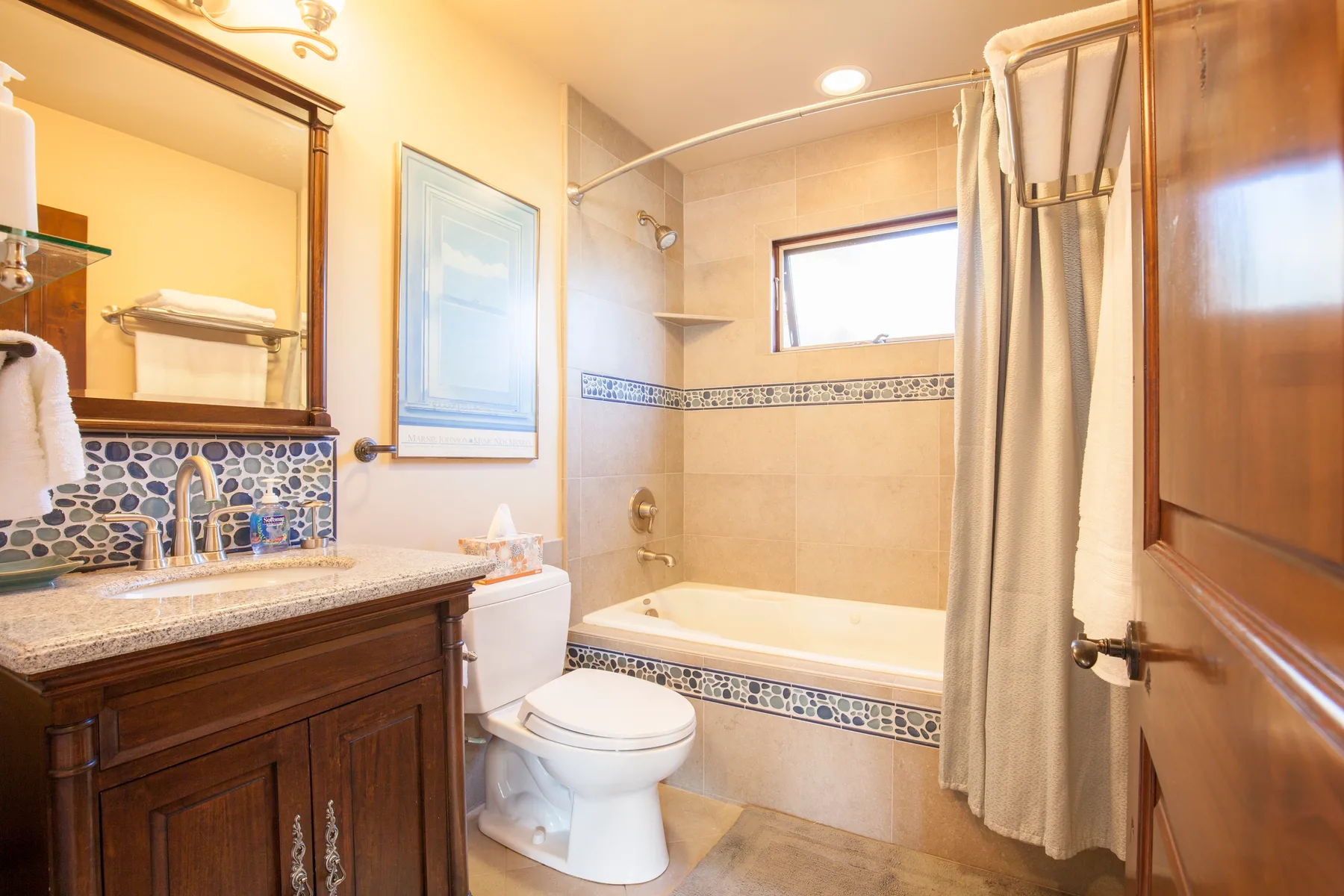 A bathroom with a bathtub, shower curtain, and vanity.