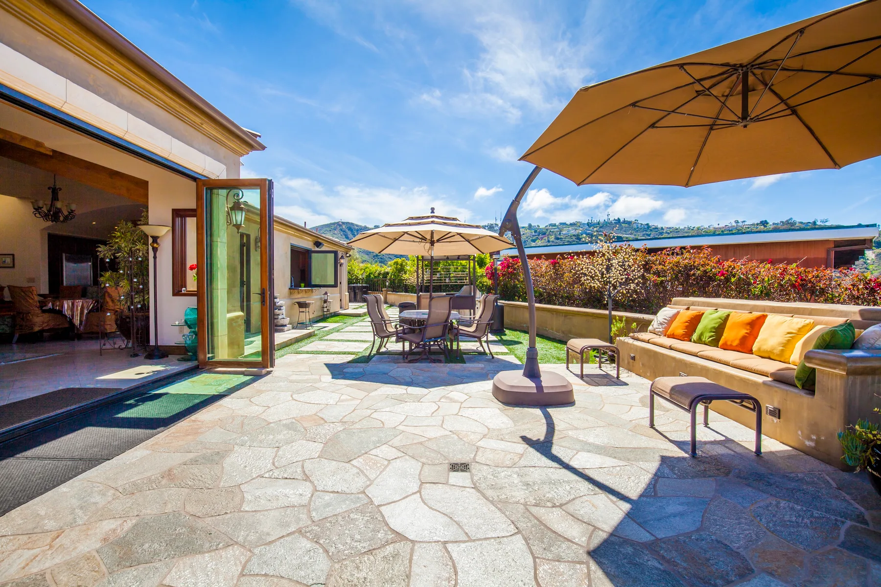 An outdoor patio with seating, large umbrellas, and a stone-paved floor.