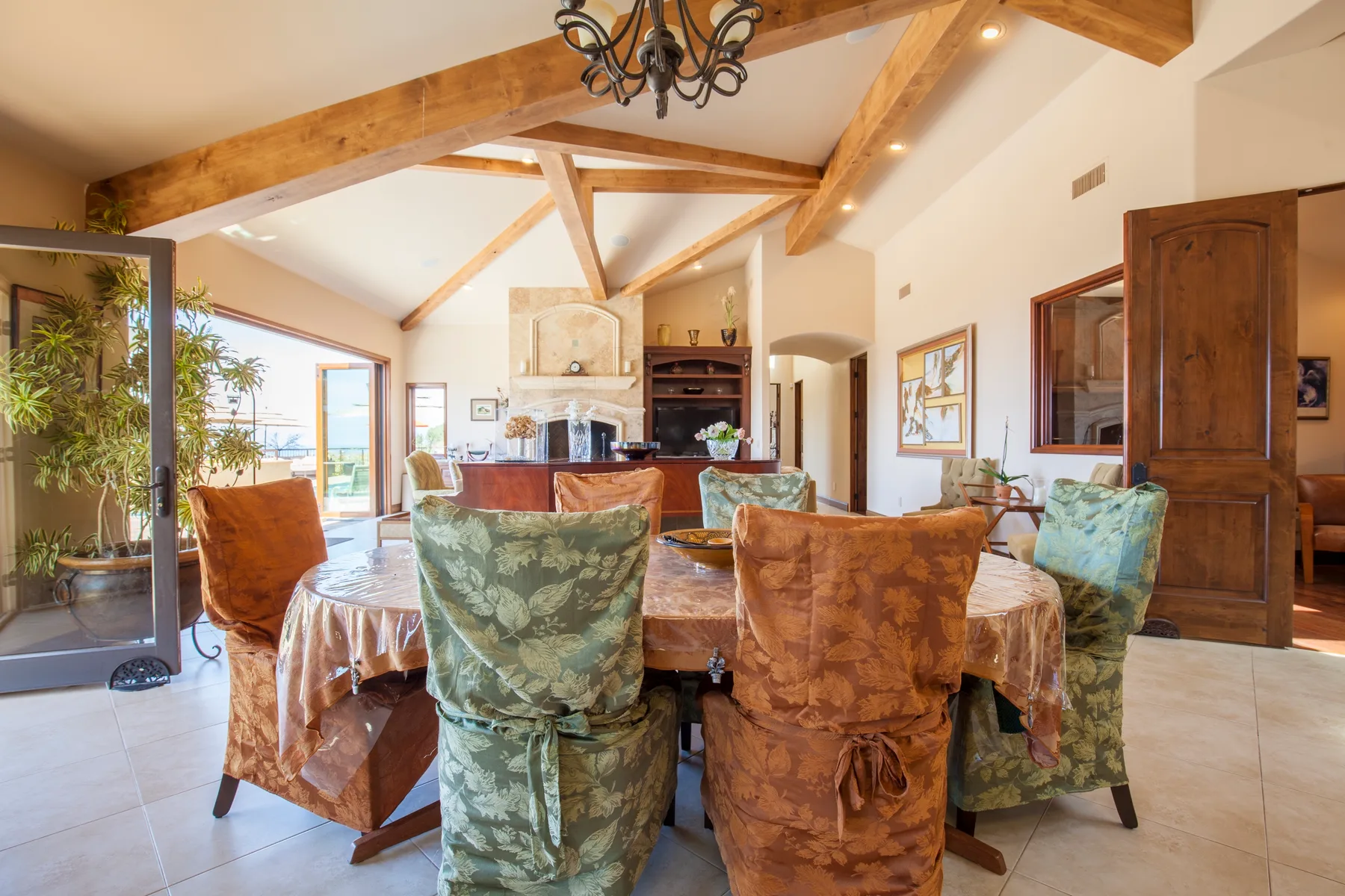 A dining area with upholstered seating beneath exposed wooden ceiling beams.