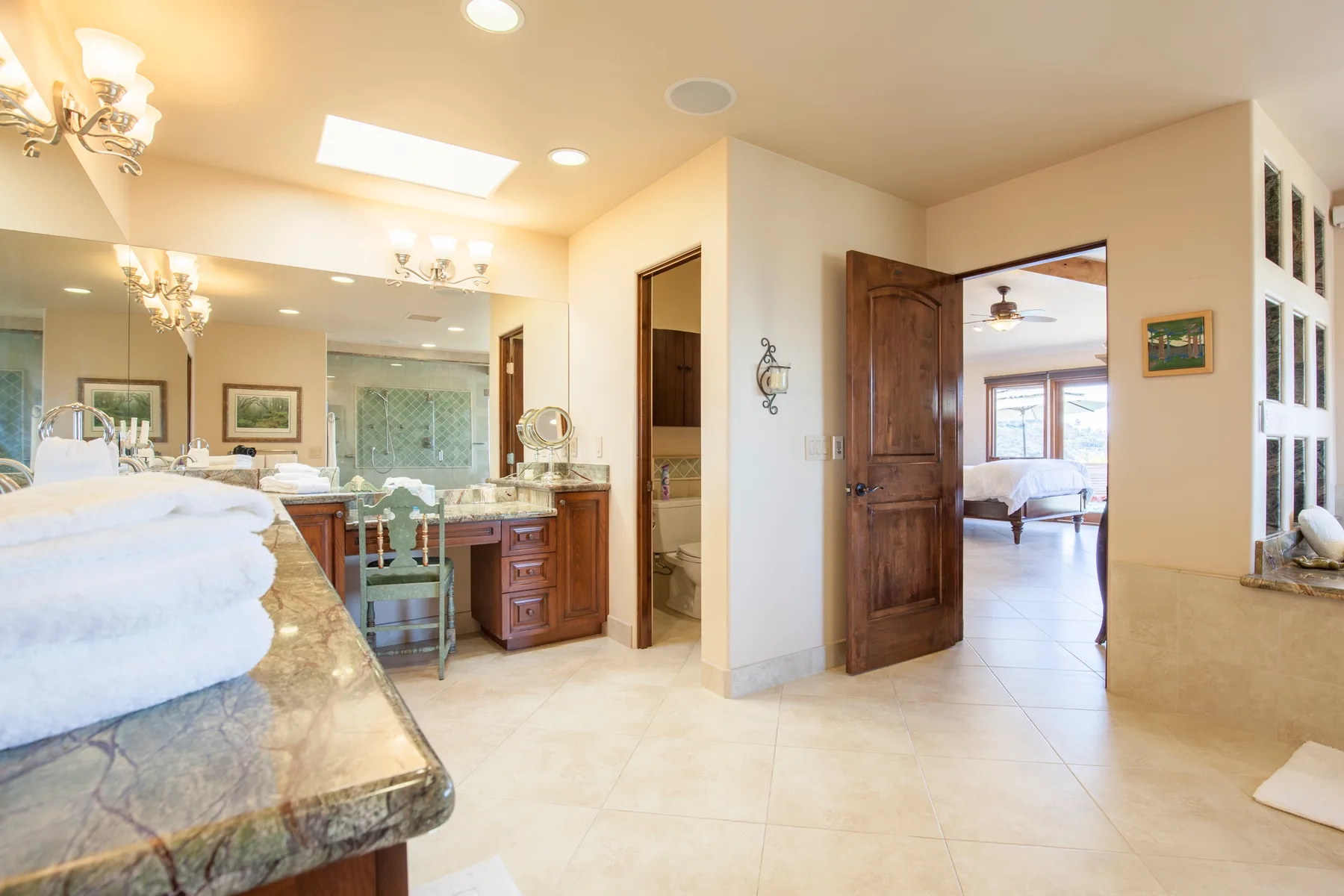 A bright bathroom vanity opens onto a bedroom through a wooden doorway.