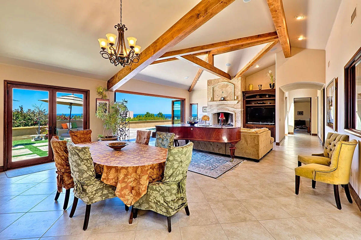 An open-plan living and dining room with exposed wooden ceiling beams.