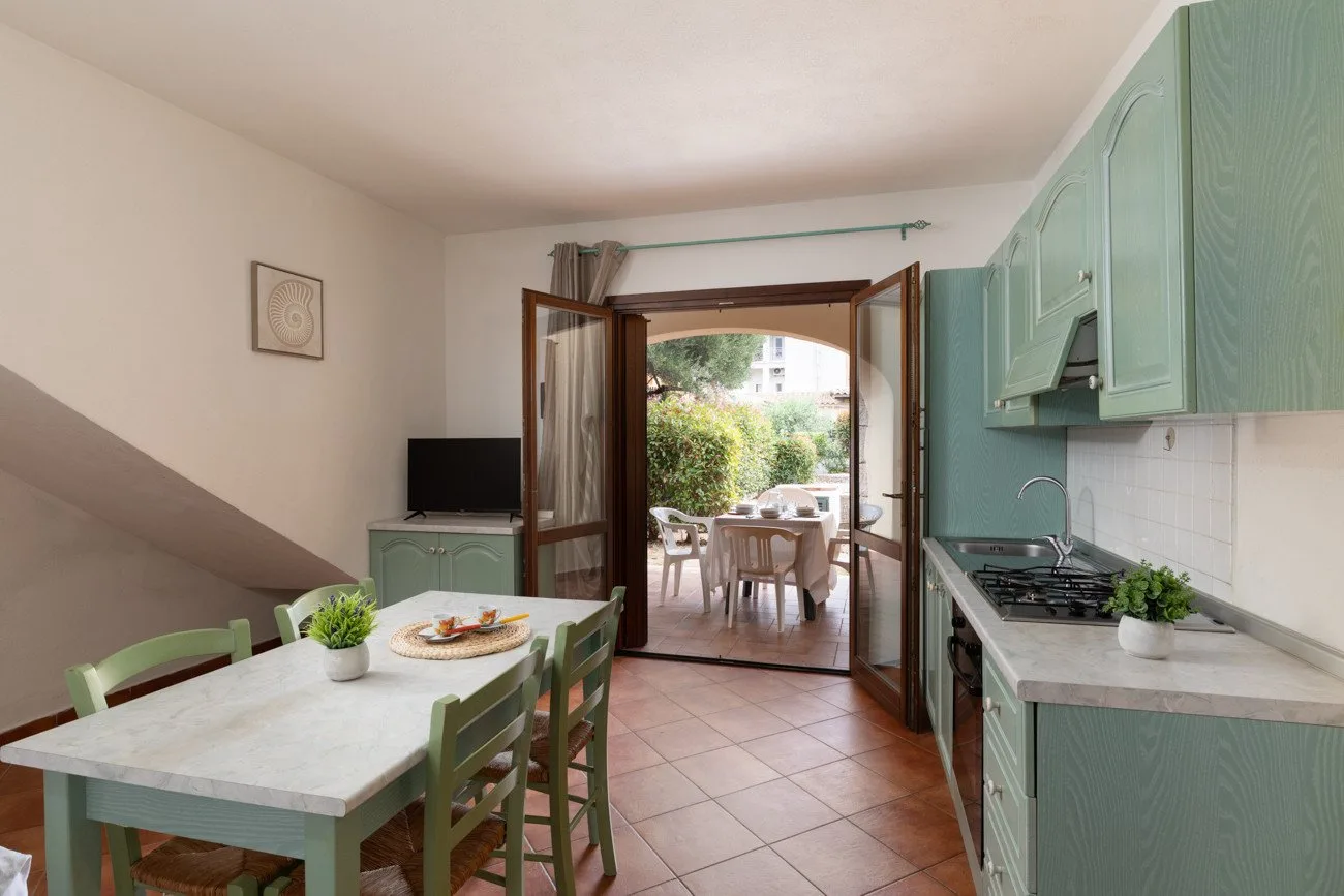 Un comedor y una cocina se abren a un patio exterior mediante puertas dobles.