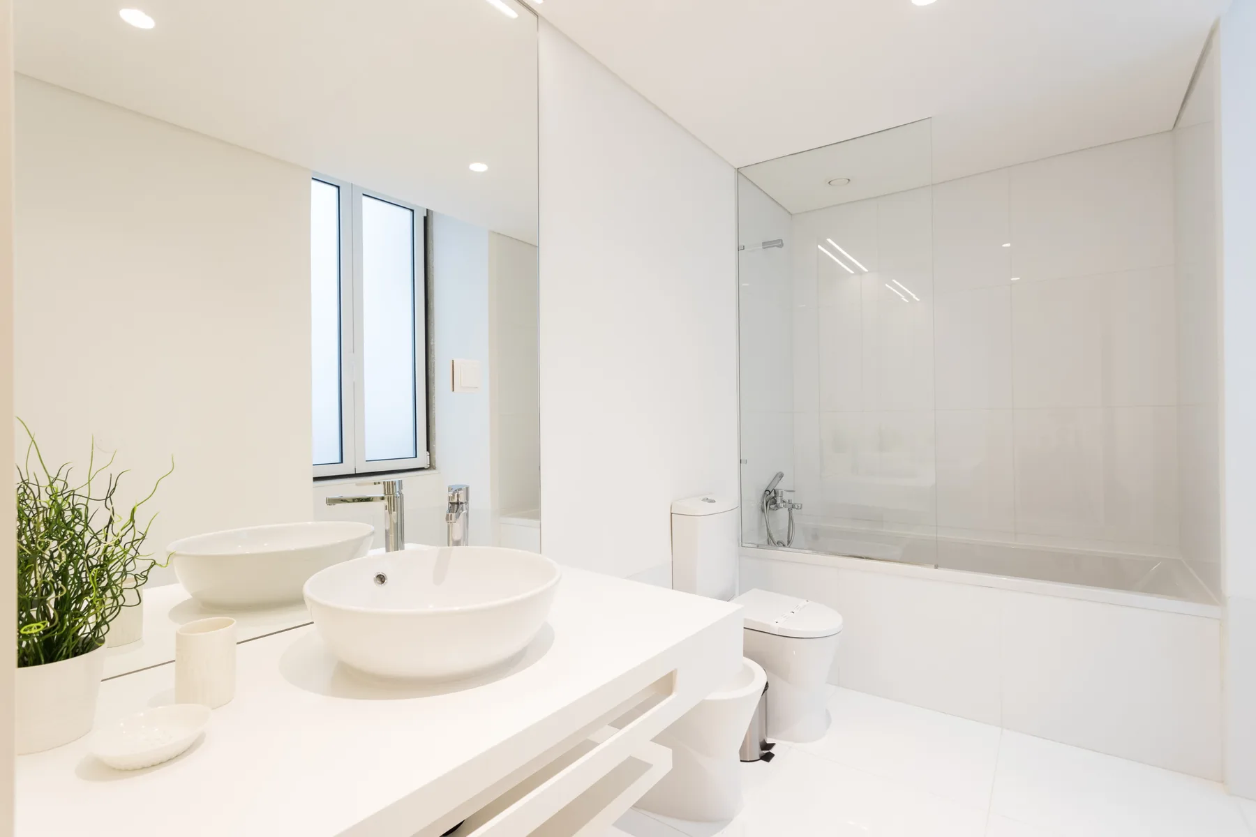 Un baño luminoso con una amplia encimera de lavabo y una ducha con mampara de vidrio.