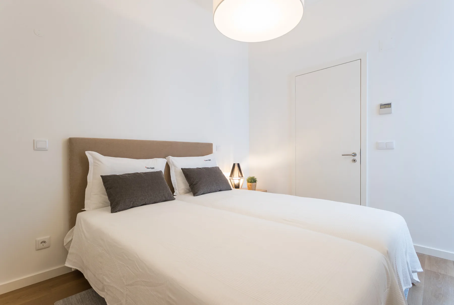 Un dormitorio con una cama doble, almohadas oscuras y una puerta cerrada.