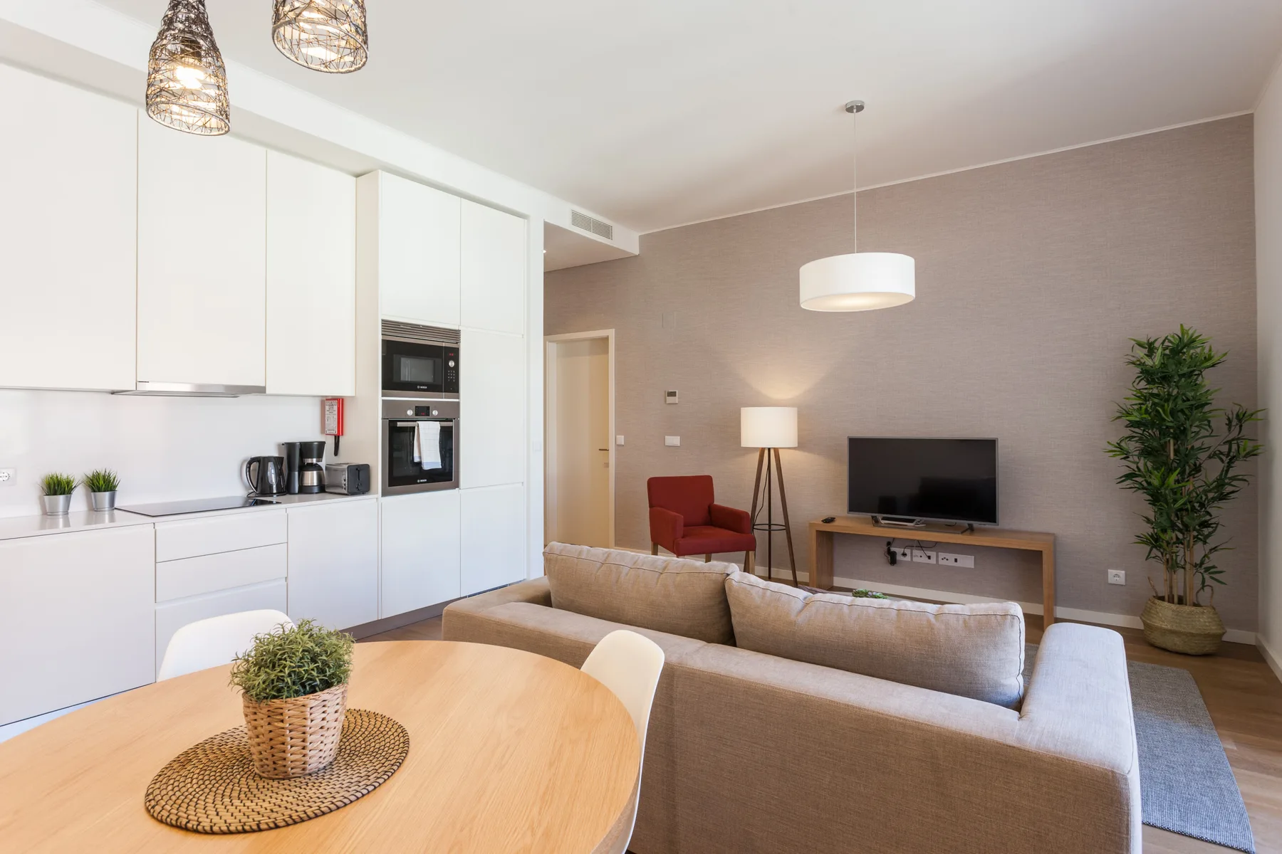 Sala de estar y cocina de planta abierta con una mesa de comedor y un televisor.