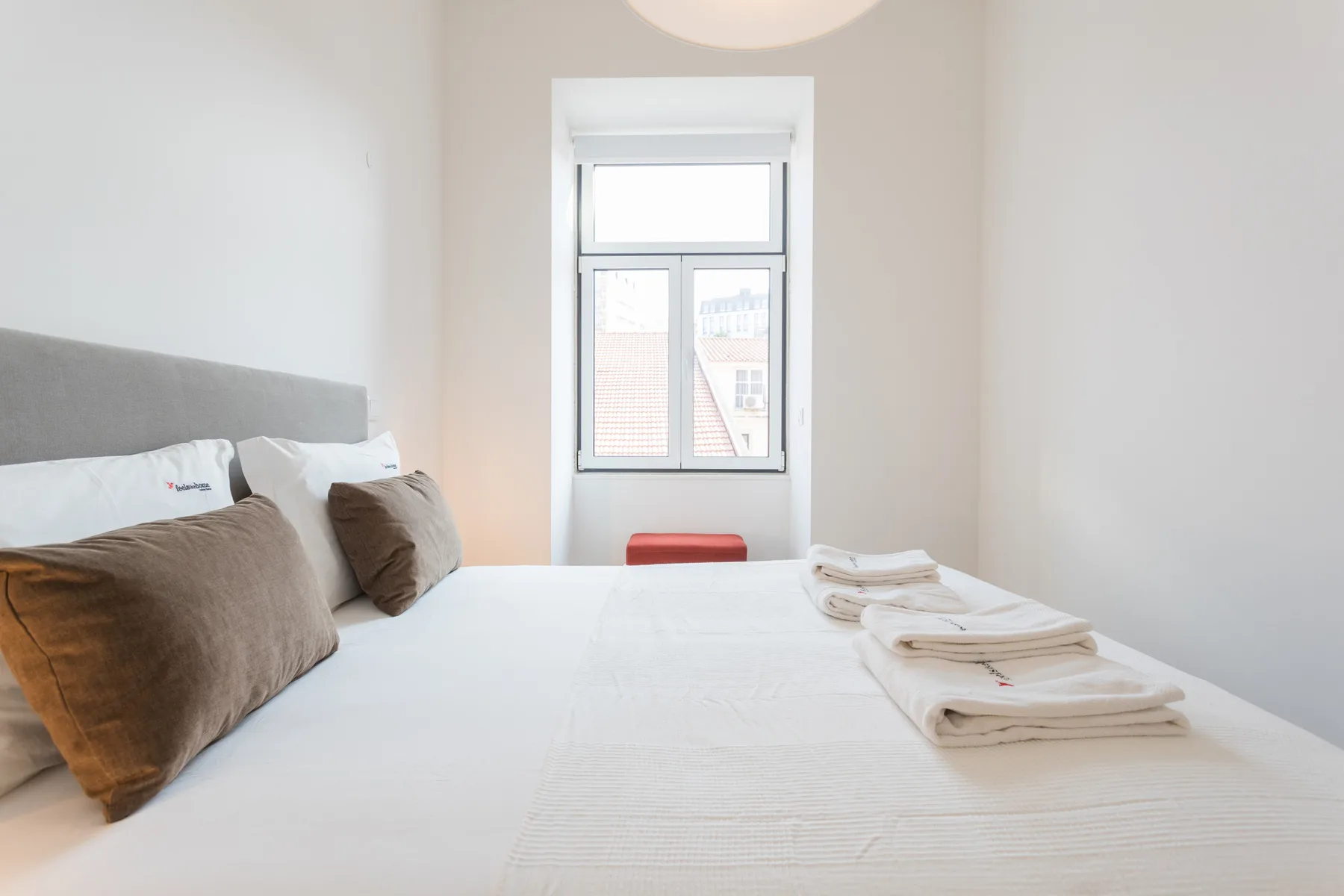 Dormitorio con una cama, toallas dobladas y una ventana.