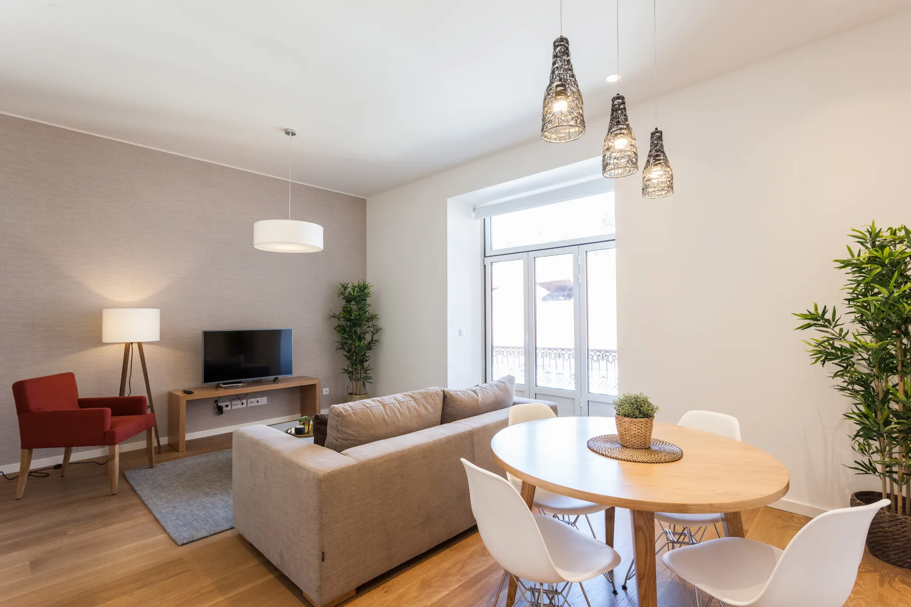 Una sala de estar y comedor con sofá, televisor y mesa redonda junto a la ventana.