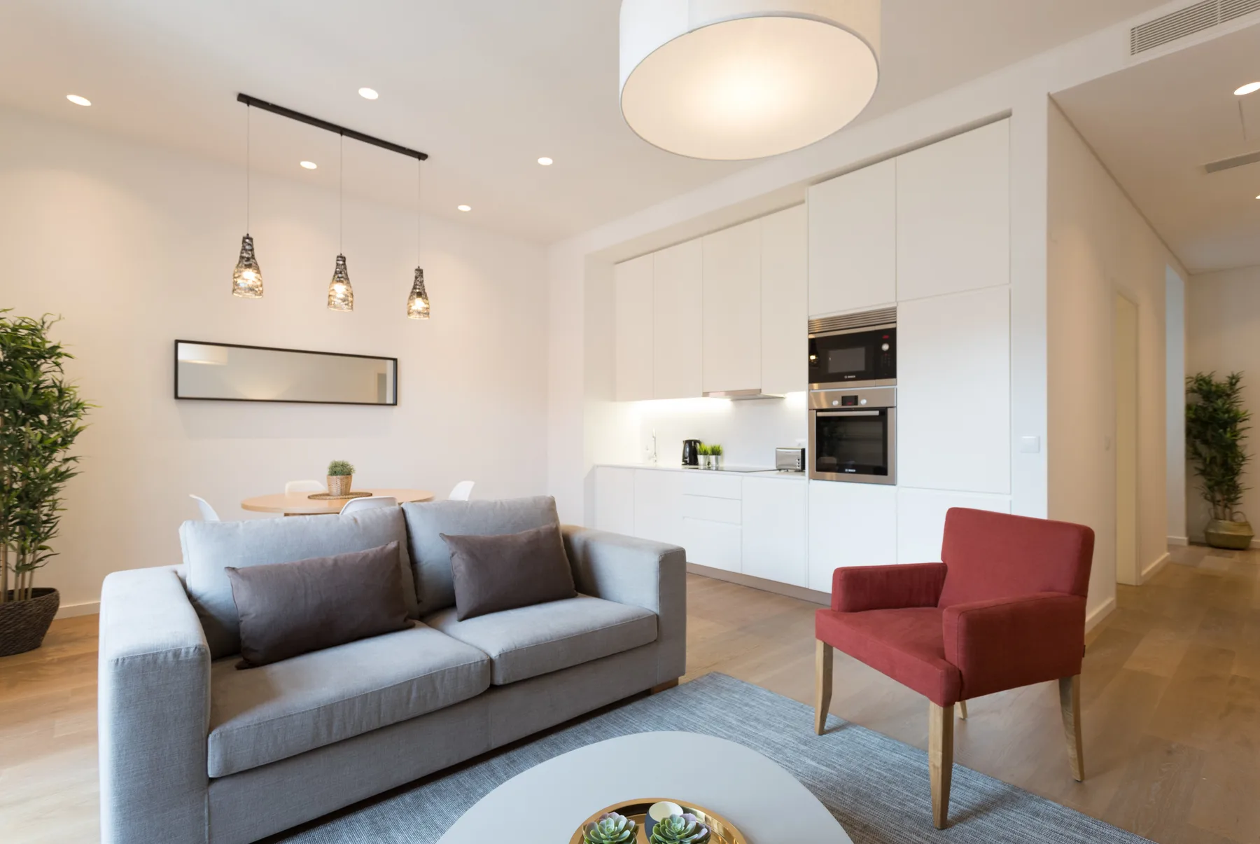 A bright living room with a gray sofa and a red armchair.