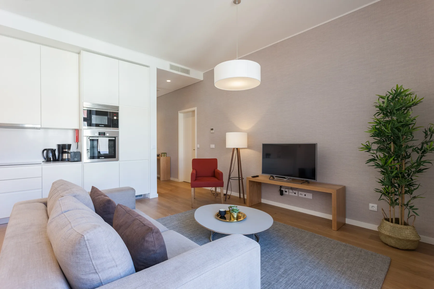 Sala de estar con asientos, un televisor y una cocina abierta.