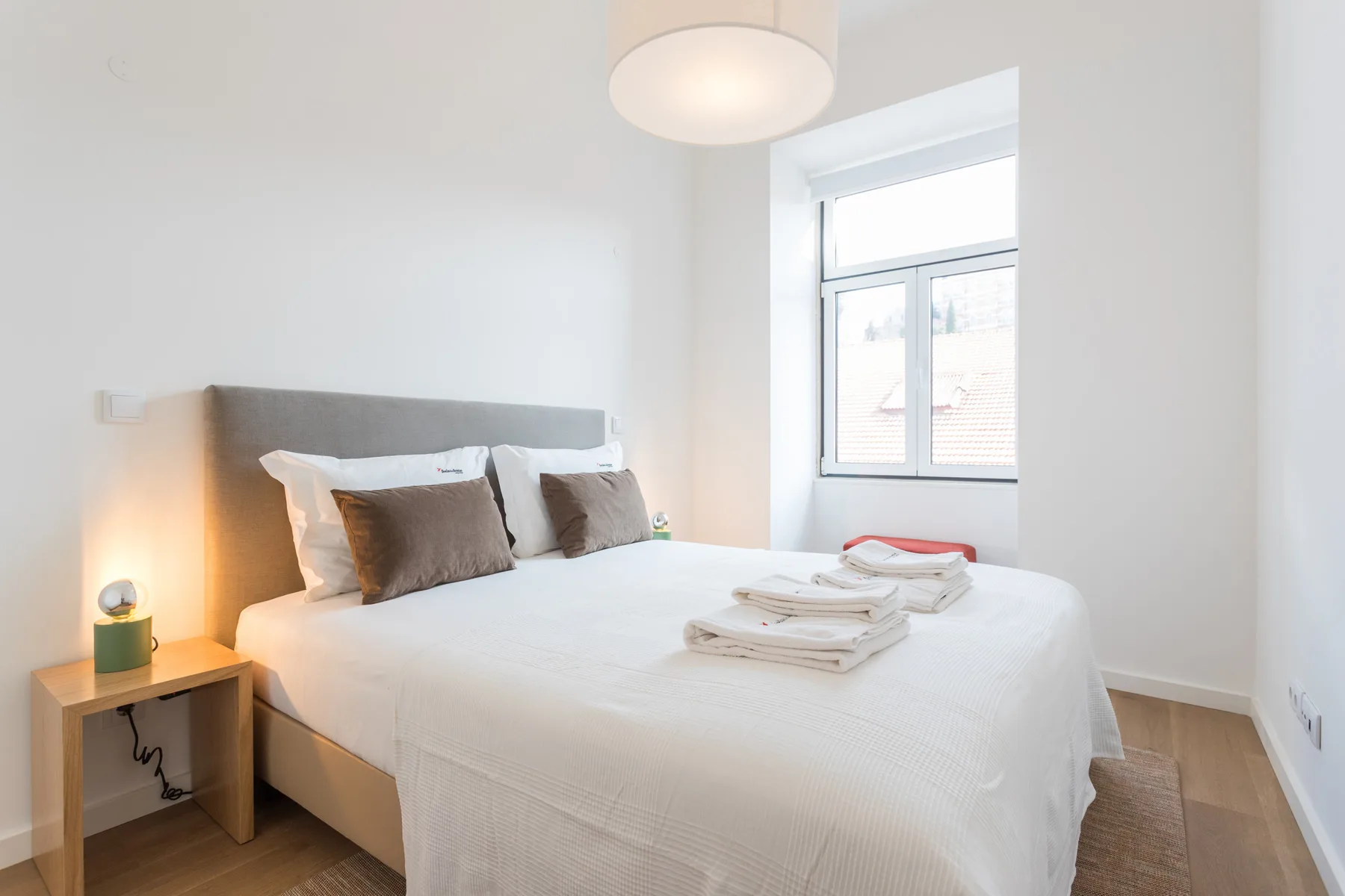 A bright bedroom with a neatly made bed and folded towels.