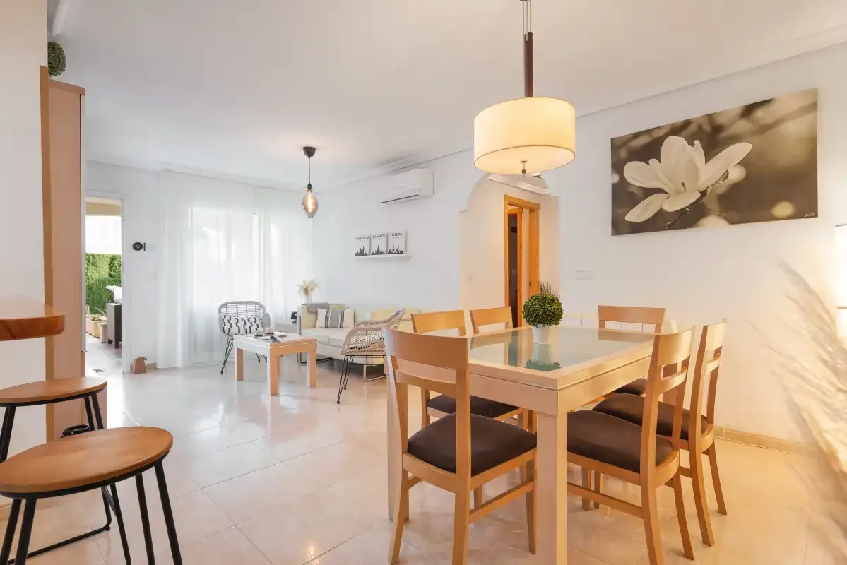A bright dining area with wooden seating, a table, and a floral wall picture.